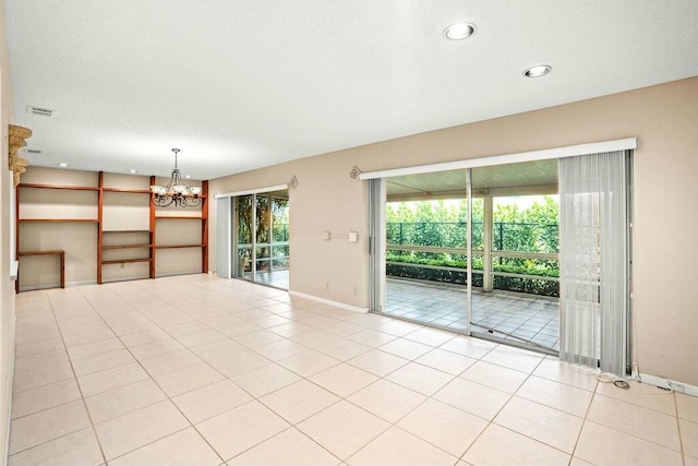 spare room featuring light tile patterned floors and an inviting chandelier