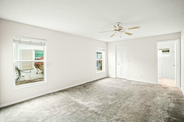 carpeted spare room with a wealth of natural light, ceiling fan, and a textured ceiling