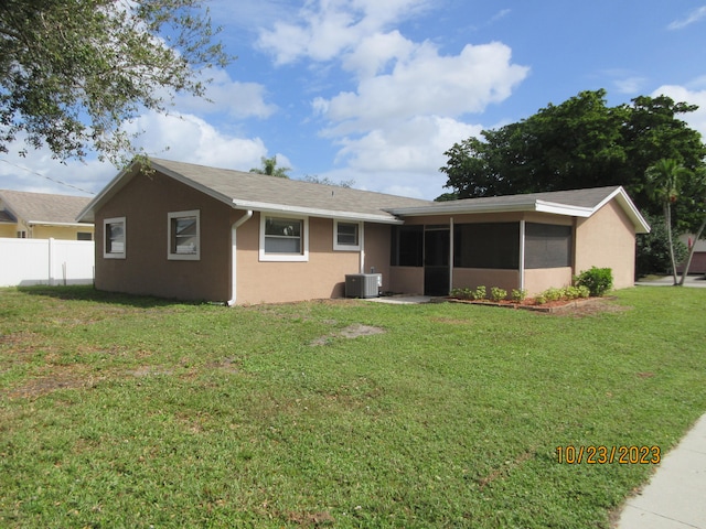 view of front facade with a front lawn, a sunroom, and cooling unit