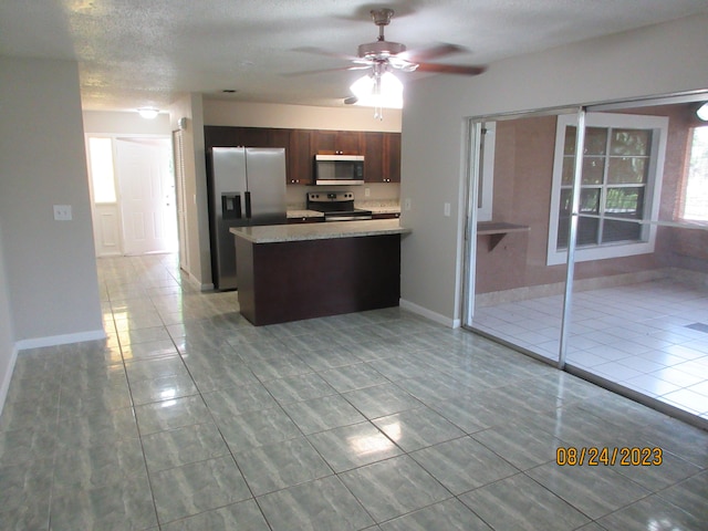 kitchen with stainless steel appliances, ceiling fan, a textured ceiling, and light tile patterned floors