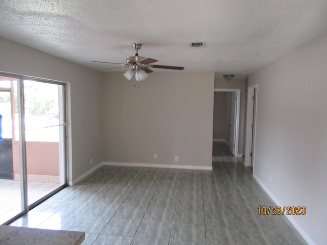 empty room featuring a textured ceiling, dark wood-type flooring, and ceiling fan