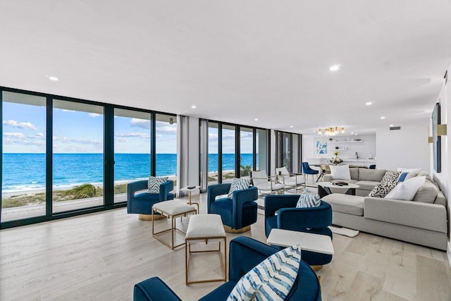 living room with light wood-type flooring, a water view, and a healthy amount of sunlight