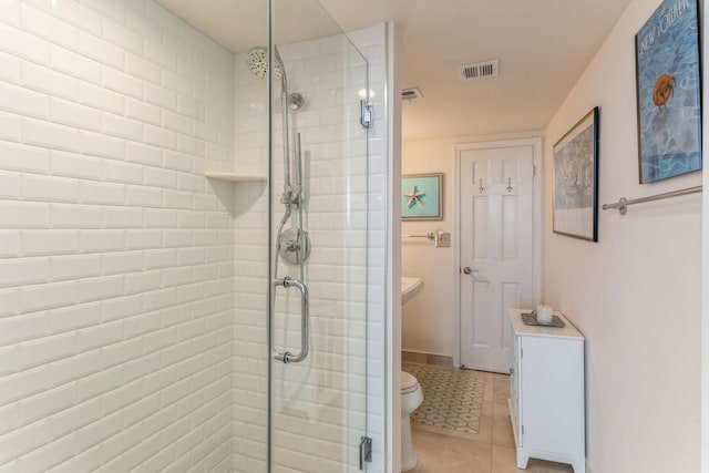 bathroom featuring a shower with door, tile patterned flooring, and toilet