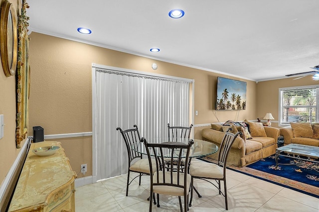 tiled dining area with ceiling fan and ornamental molding