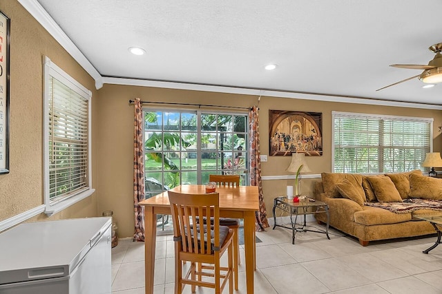 tiled dining room with a textured ceiling, ceiling fan, and crown molding