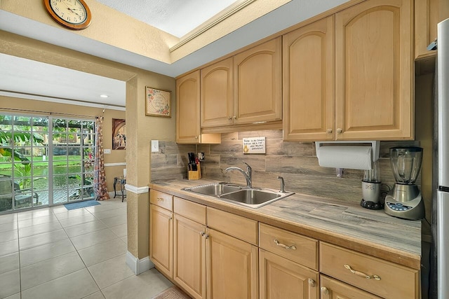 kitchen with light brown cabinets, tasteful backsplash, light tile patterned floors, and sink