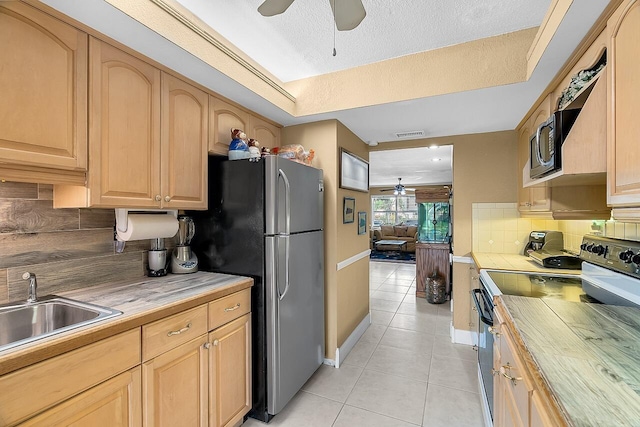 kitchen with light brown cabinetry, backsplash, stainless steel appliances, and a textured ceiling