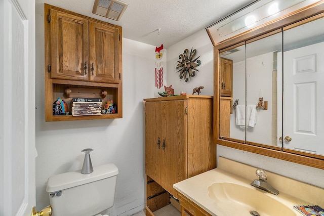 bathroom featuring vanity, a textured ceiling, and toilet