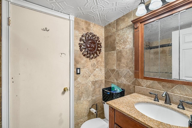 bathroom with vanity, toilet, tile walls, and tasteful backsplash