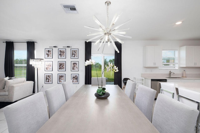 tiled dining space featuring a chandelier, a wealth of natural light, and sink