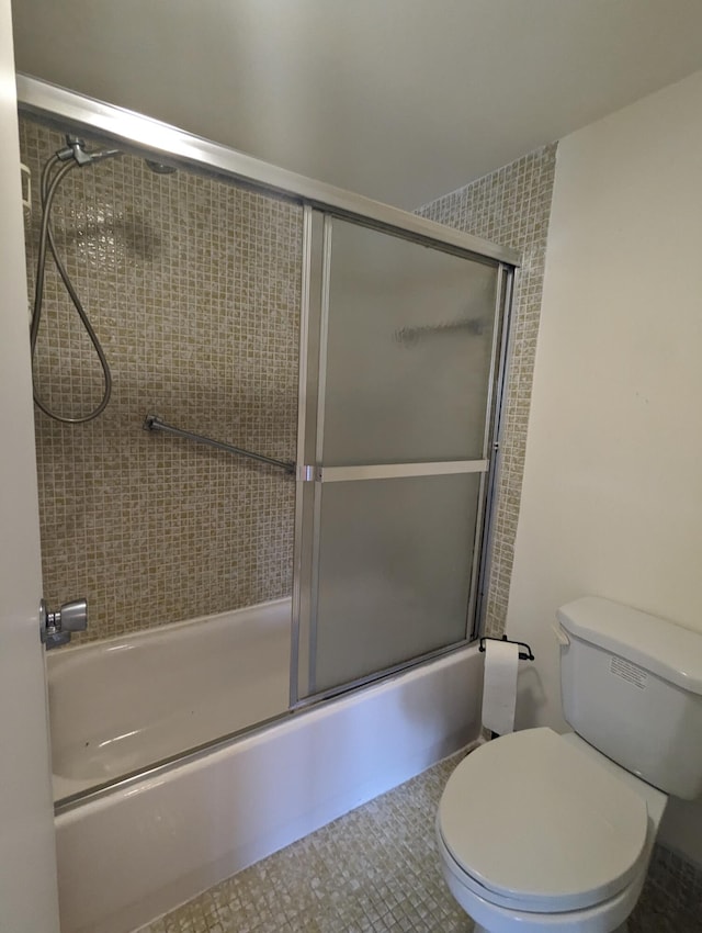 bathroom featuring bath / shower combo with glass door, tile patterned floors, and toilet