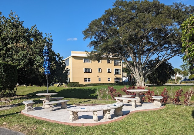 view of property's community featuring a lawn and a patio area