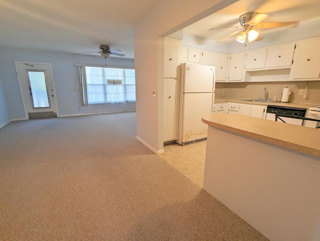 kitchen with sink, ceiling fan, white cabinets, light colored carpet, and white fridge