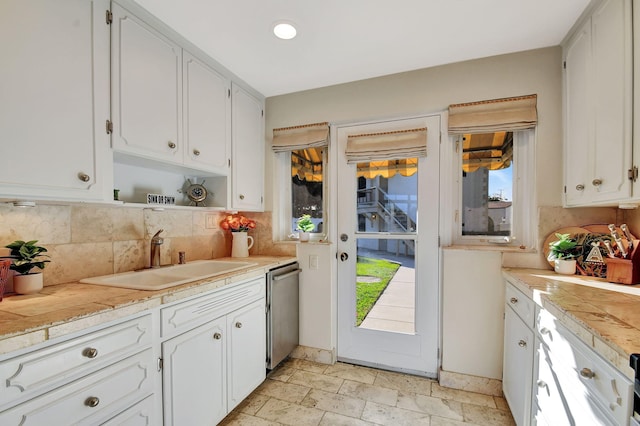 kitchen with sink, white cabinetry, backsplash, and dishwasher