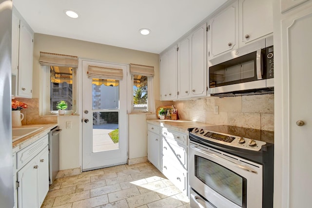 kitchen featuring white cabinets, backsplash, and appliances with stainless steel finishes