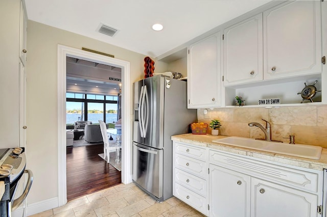 kitchen featuring sink, a water view, appliances with stainless steel finishes, and white cabinetry