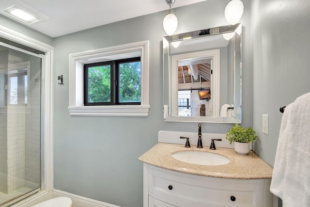 bathroom featuring a shower with door and vanity