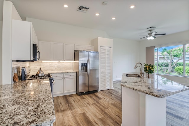 kitchen featuring light stone countertops, white cabinetry, sink, light hardwood / wood-style flooring, and appliances with stainless steel finishes