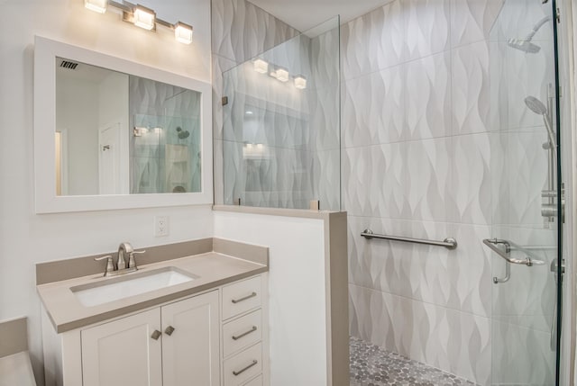 bathroom with a tile shower and vanity