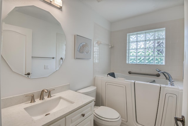 bathroom with vanity, toilet, and a tub to relax in