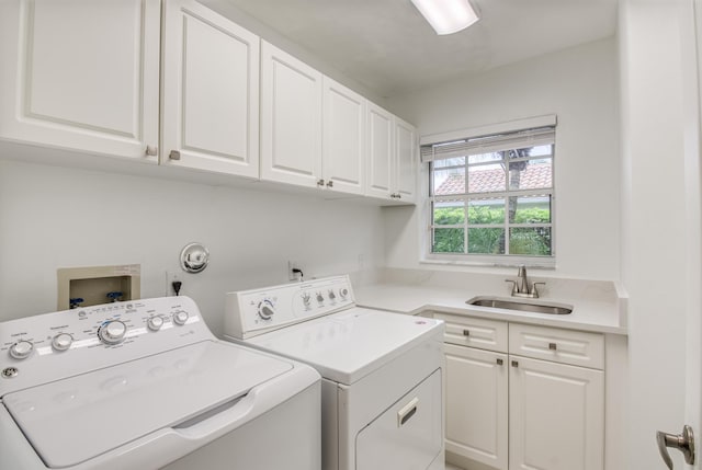 washroom with cabinets, washer and dryer, and sink