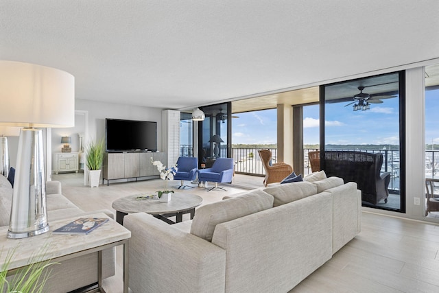 living room with a wall of windows, ceiling fan, and a textured ceiling