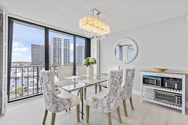 dining room with hardwood / wood-style flooring, a water view, a healthy amount of sunlight, and a chandelier