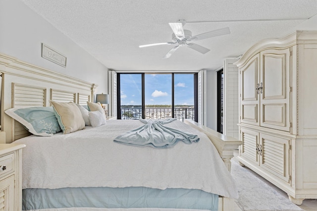 bedroom with a textured ceiling, access to outside, ceiling fan, and floor to ceiling windows