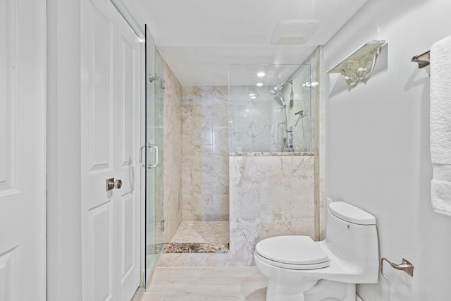 bathroom with a shower with shower door and toilet