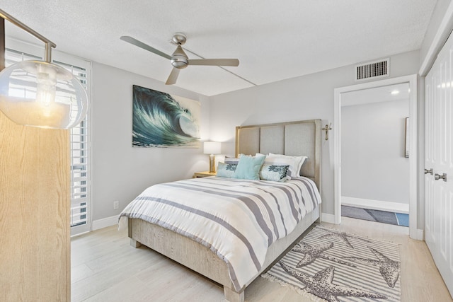 bedroom with ceiling fan, a textured ceiling, and light hardwood / wood-style flooring