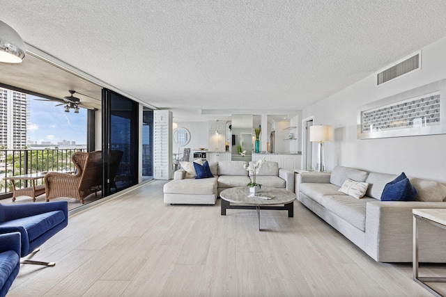 living room with expansive windows, a textured ceiling, and light hardwood / wood-style flooring