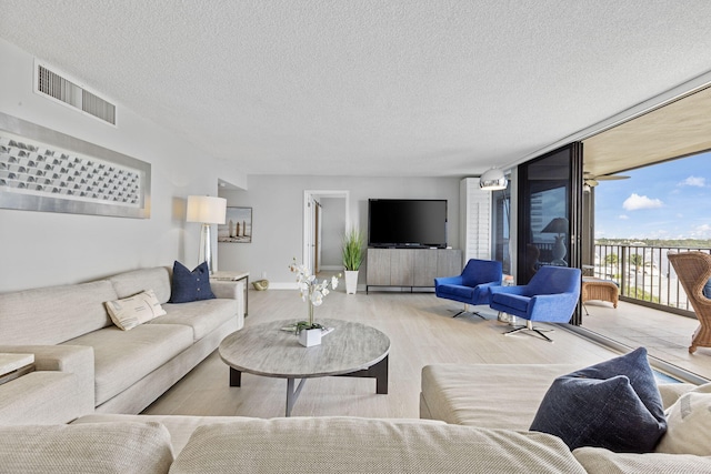 living room featuring expansive windows, light hardwood / wood-style flooring, a textured ceiling, and ceiling fan