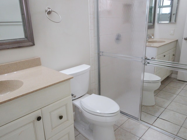 bathroom with tile patterned flooring, vanity, toilet, and a shower with shower door