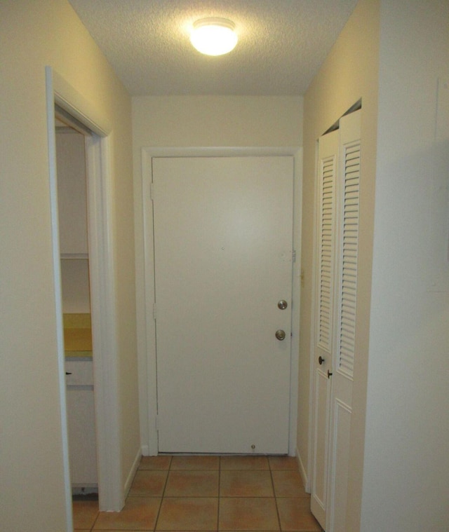 corridor featuring light tile patterned floors and a textured ceiling