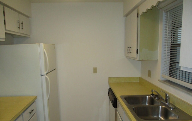 kitchen featuring white cabinets, white appliances, light countertops, and a sink