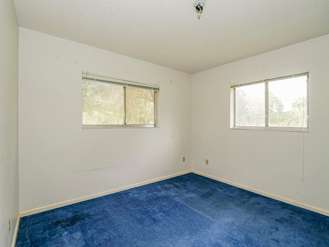 unfurnished room featuring a textured ceiling and dark carpet