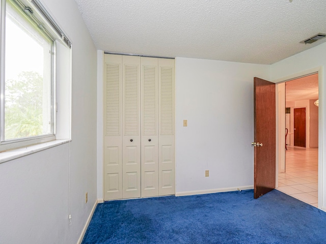 unfurnished bedroom with a textured ceiling, a closet, and carpet