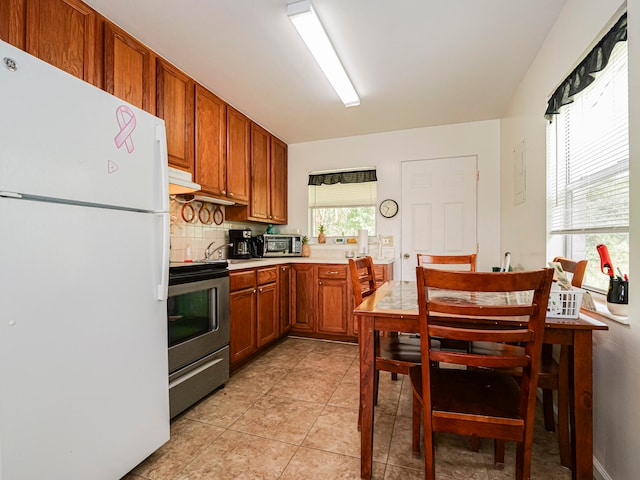 kitchen with light tile patterned floors, backsplash, and appliances with stainless steel finishes