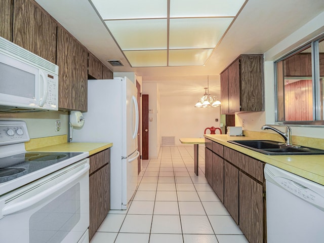 kitchen with hanging light fixtures, sink, a notable chandelier, light tile patterned floors, and white appliances