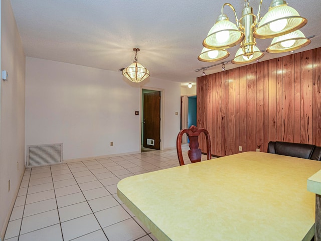 dining space with wooden walls, light tile patterned floors, and a textured ceiling