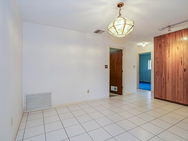 empty room featuring rail lighting, a textured ceiling, and light tile patterned flooring