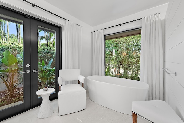 bathroom with a bathtub, concrete floors, and french doors