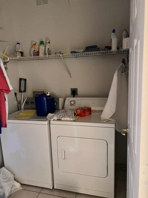 laundry area featuring washing machine and clothes dryer and light tile patterned flooring