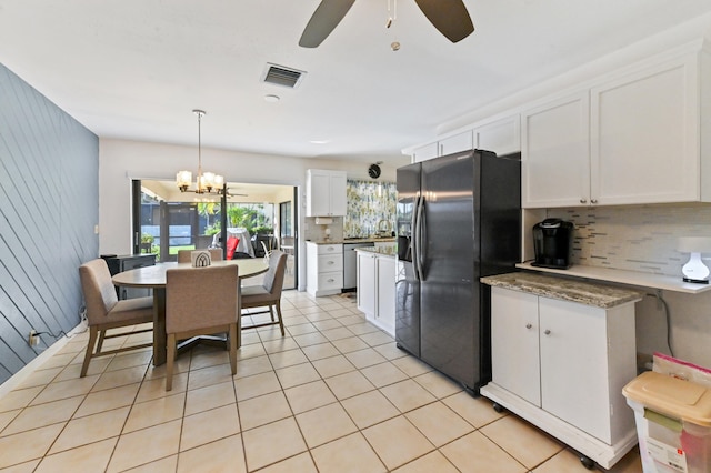 kitchen with ceiling fan with notable chandelier, stainless steel appliances, decorative light fixtures, white cabinetry, and wood walls