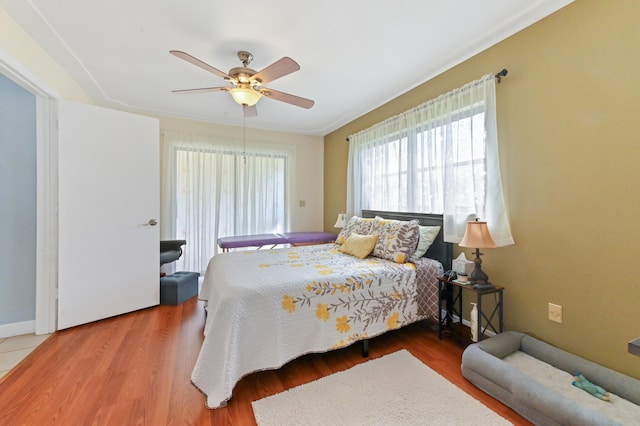 bedroom with hardwood / wood-style flooring, ceiling fan, and crown molding