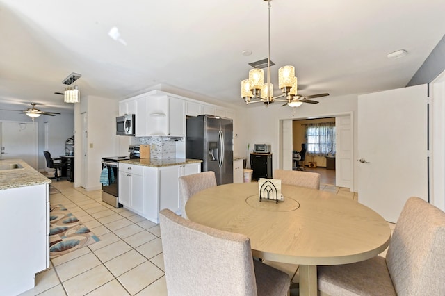 tiled dining room with ceiling fan with notable chandelier and sink