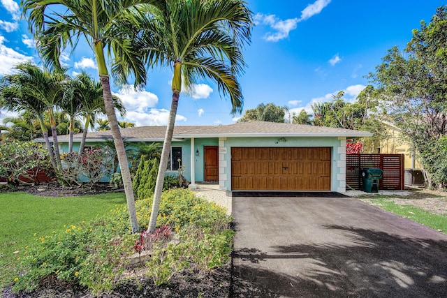 ranch-style home featuring a front yard, a garage, and central air condition unit