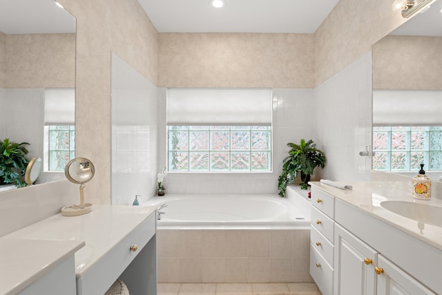 bathroom with tile patterned floors, vanity, a relaxing tiled tub, and tile walls