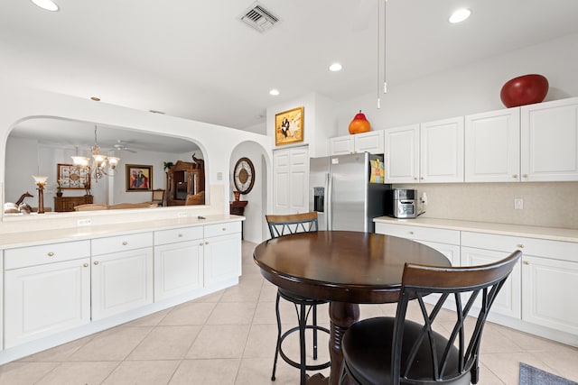 kitchen featuring white cabinetry, stainless steel refrigerator with ice dispenser, light tile patterned flooring, decorative light fixtures, and a chandelier