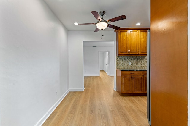 kitchen with backsplash, light hardwood / wood-style flooring, ceiling fan, and dark stone counters